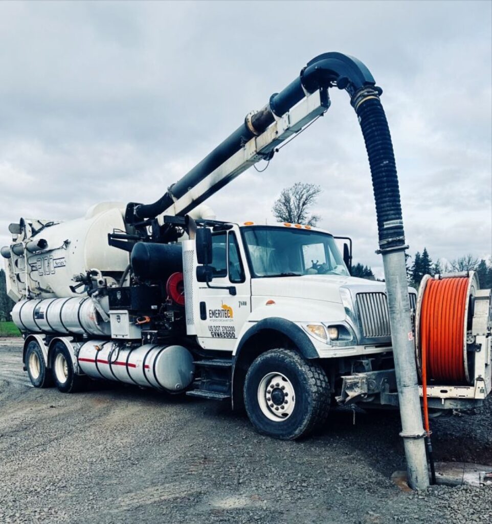 Hydrovac, A hydro excavation truck operating in Vancouver, Washington, on a construction site near the Columbia River. High-pressure water digs through the soil, demonstrating a non-destructive method ideal for urban areas with dense underground utilities